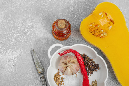 Half butternut squash with olive oil, sea salt, pepper, and chili. Vegan healthy eating, autumn harvest, farm-to-table cooking, light stone background, top viewの写真素材