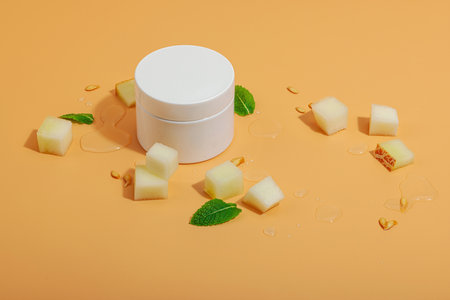 Natural melon extract skincare products. Hydrating cream jar, lotion bottle, mint leaves, and fresh...