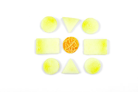 Geometric pattern of fresh melon pieces cut into squares, circles, and triangles. Abstract food design on a white background, top viewの写真素材