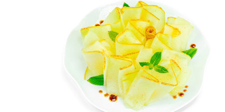 Thinly sliced melon carpaccio appetizer with fresh mint and balsamic sauce drops on a white plate. Gourmet isolated food design for dining, banner formatの写真素材