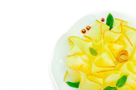 Thinly sliced melon carpaccio appetizer with fresh mint and balsamic sauce drops on a white plate. Gourmet isolated food design for healthy dining, top viewの写真素材