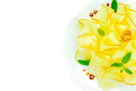 Thinly sliced melon carpaccio appetizer with fresh mint and balsamic sauce drops on a white plate. Gourmet isolated food design for healthy dining, top viewの写真素材