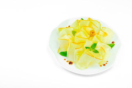 Thinly sliced melon carpaccio appetizer with fresh mint and balsamic sauce drops on a white plate. Gourmet isolated food design for healthy dining, copy spaceの写真素材