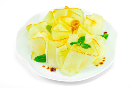 Thinly sliced melon carpaccio appetizer with fresh mint and balsamic sauce drops on a white plate. Gourmet isolated food design for healthy dining, close upの写真素材