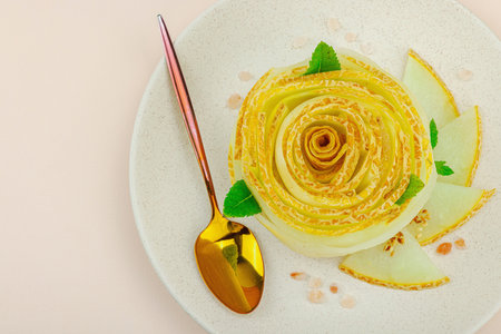 Elegant melon carpaccio dessert shaped like a flower, garnished with mint, spices and pink salt...