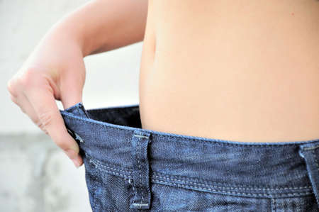 Woman proving wieght loss by whearing old pantsの写真素材