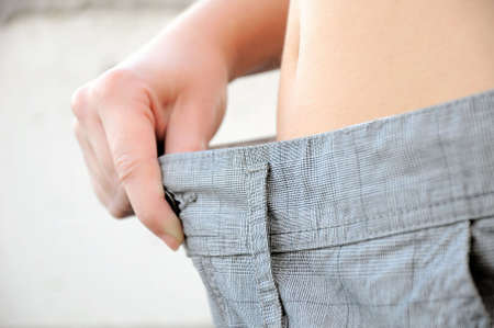 Woman proving wieght loss by whearing old pantsの写真素材