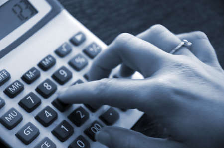 Woman typing on an hand calculatorの写真素材