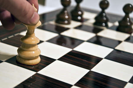 Man hand moving queen on chess tableの写真素材