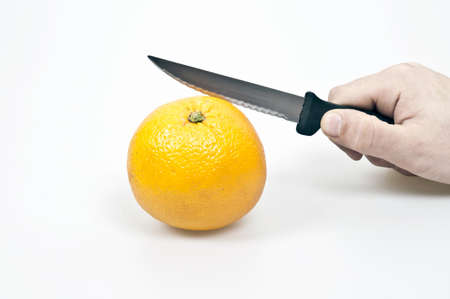 Male hand cutting orange fruitの写真素材