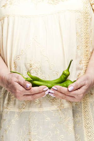 Housewife holding bunch of green peppersの写真素材