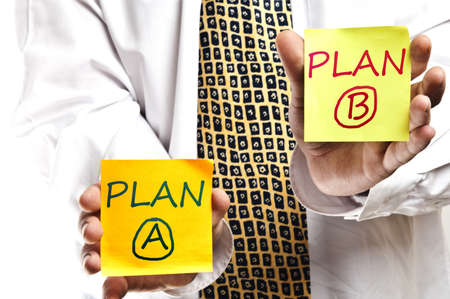Business man holding two post it with Plan A and Bの写真素材