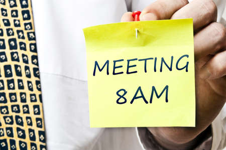 Meeting at 8 AM post it in business man handの写真素材