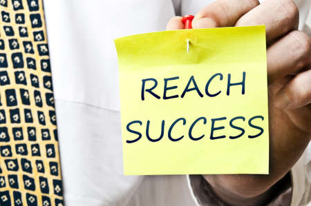 Reach succes post it in business man handの写真素材