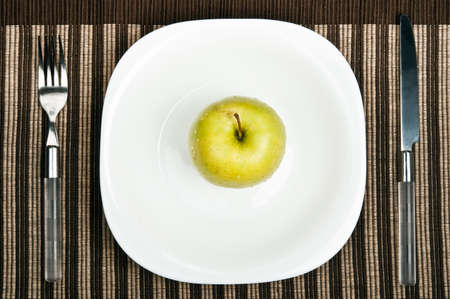 Apple on plate with fork and knifeの写真素材