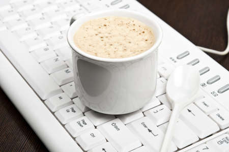 Coffee on an white keyboardの写真素材