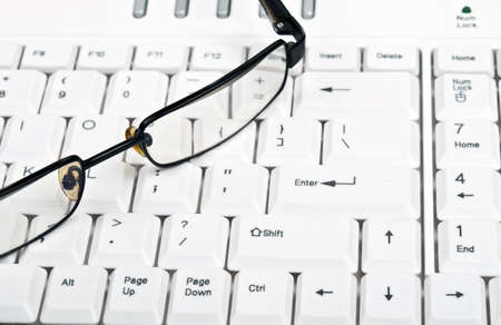Eye glasses on an white keyboardの写真素材
