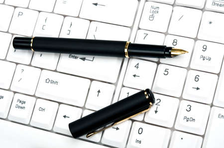 Pen on an white keyboardの写真素材