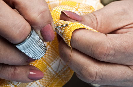 Woman hands sewing yellow material