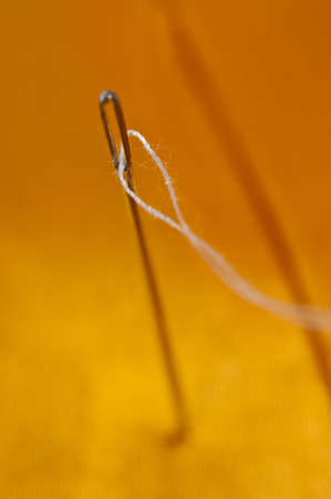 Needle with white thread on orange silkの写真素材