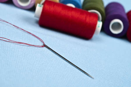 Needle and thread on blue material backgroundの写真素材
