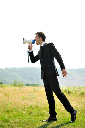 Business man with loudspaker in nature