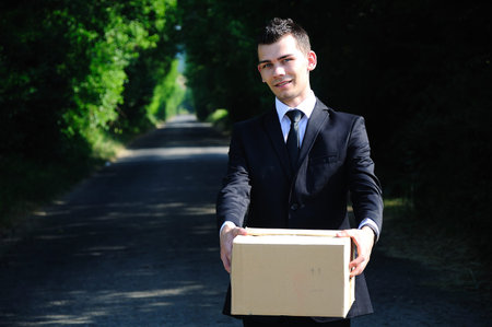 Business man delivering box on roadの写真素材