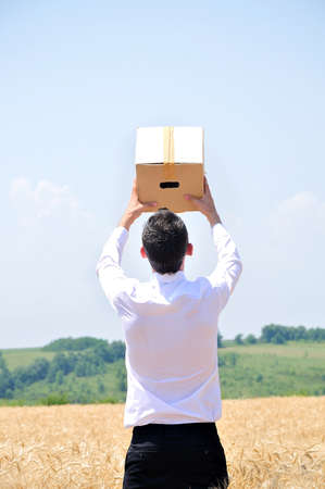 Business man delivering box in wheatの写真素材