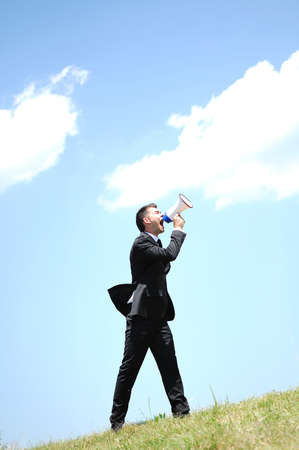 Business man with loudspaker in natureの写真素材