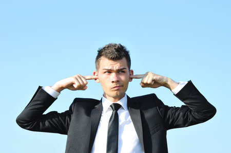 Business man with finger in ears
