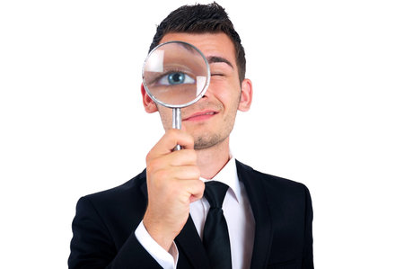 Isolated young business man with magnifying glass