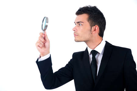 Isolated young business man with magnifying glassの写真素材