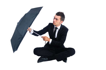 Isolated business man with umbrella sitting downの写真素材