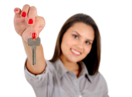 Isolated young business woman showing keysの写真素材