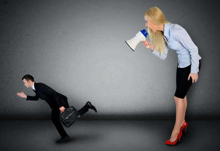 Business woman screaming on megaphone on little manの写真素材