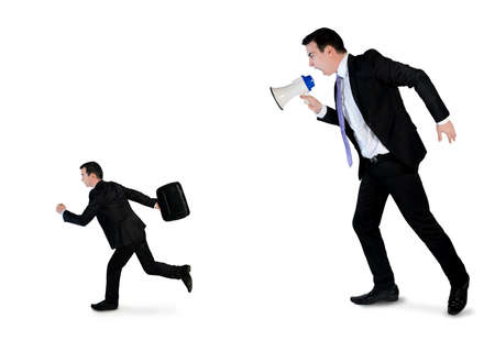 Business man screaming on megaphone on little manの写真素材