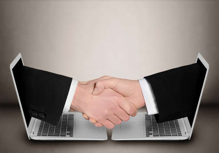 Business people handshake through computer