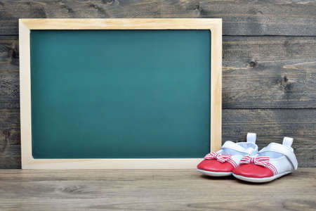 School board and kid shoes on wooden tableの写真素材