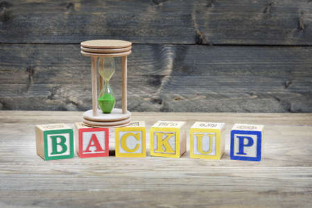 Hourglass and word backup on wooden table
