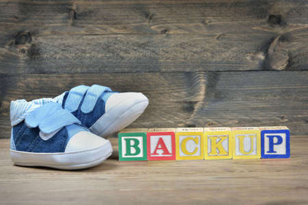 Kid shoes and word backup on wooden tableの写真素材