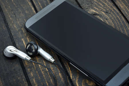 Phone and earphones on wooden tableの写真素材