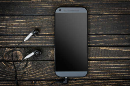 Phone and earphones on wooden tableの写真素材