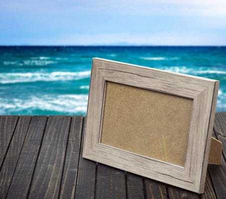 Photo frame on wooden table and sea