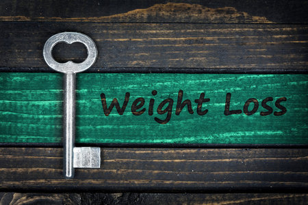 Weight Loss word and old key on wooden table