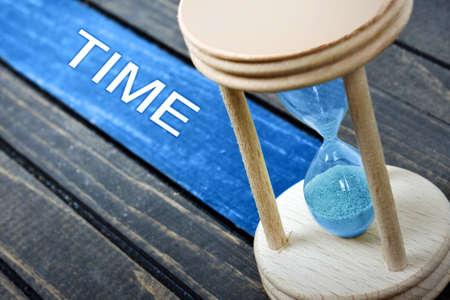 Time text and hourglass on wooden tableの写真素材