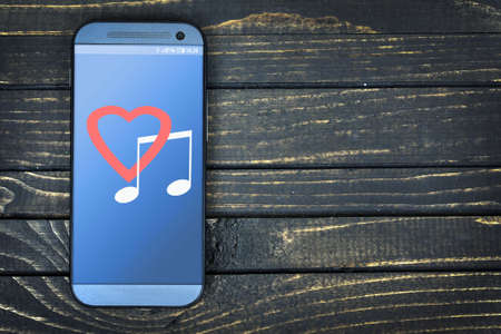 Love music on phone screen over wooden tableの写真素材