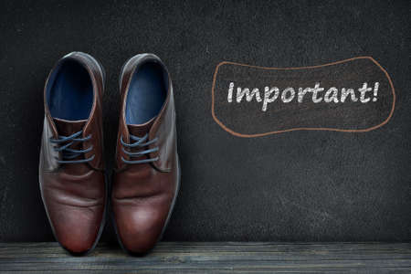 Important text on black board and business shoes on wooden floorの写真素材