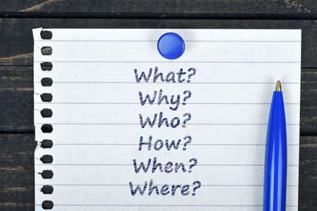 Questions text on page and pen on wooden tableの写真素材