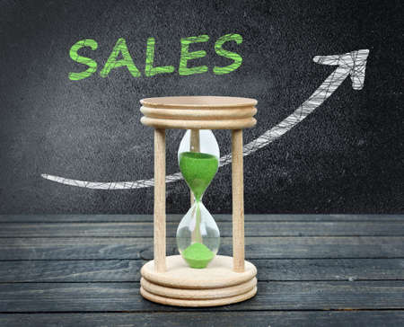 Sales and hourglass close-up on wooden tableの写真素材