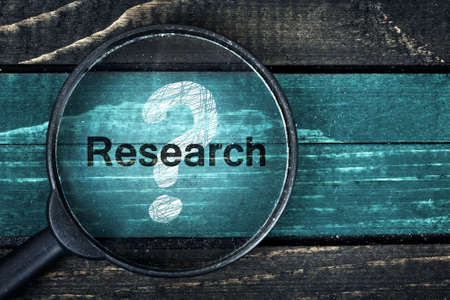 Research text painted and magnifying glass on wooden tableの写真素材